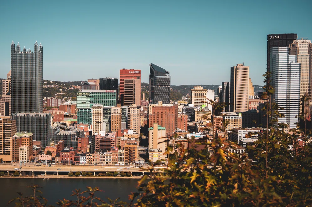 Horizontal view above the river in downtown Pittsburgh at sunset, with our new dealership location just north of the city